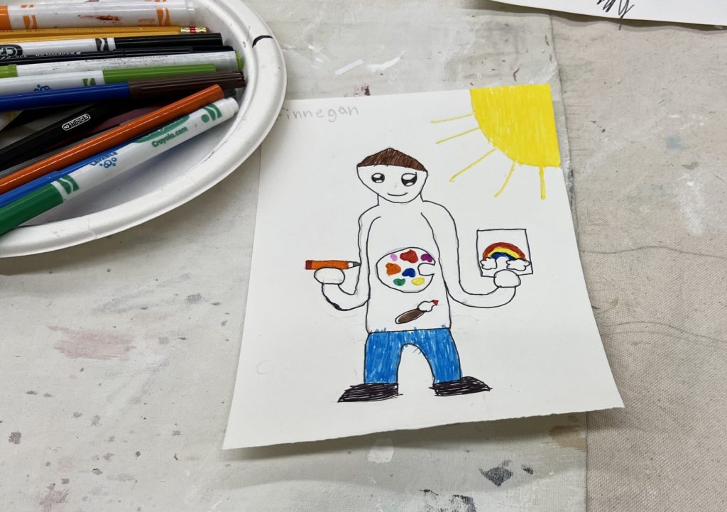 Image of a drawing made with markers of a person in jeans holding a hand-drawn picture of a rainbow