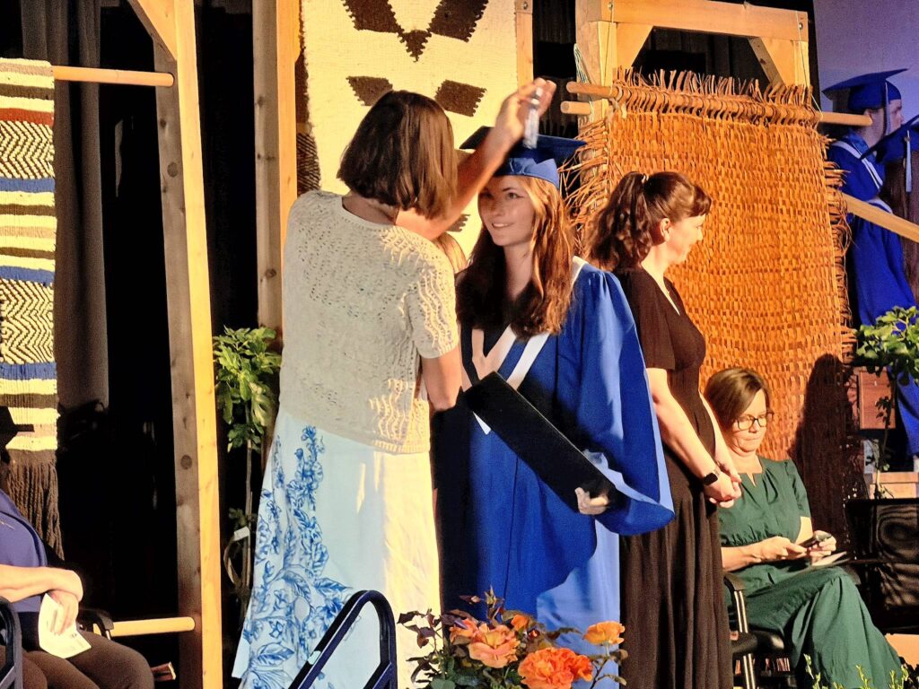 grad accepts diploma as her tassel is moved to the left