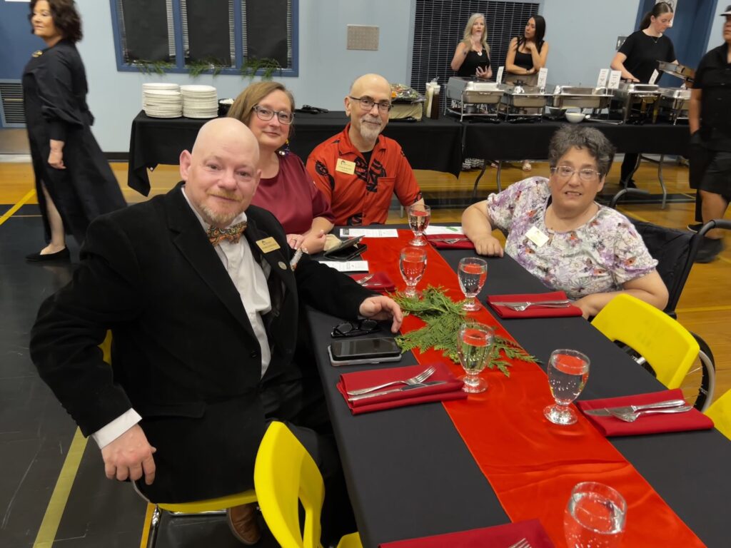 4 trustees sat at a table, smiling to the camera
