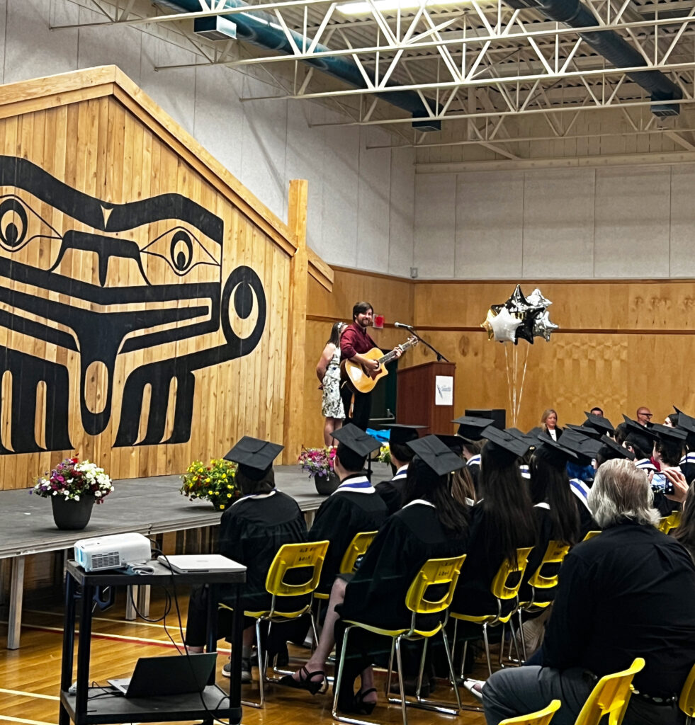 Island ConnectED grad teacher playing guitar on stage