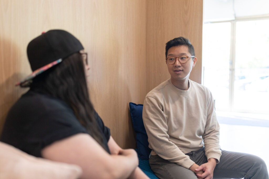 two people chatting, man with glasses and younger woman with hat (out of focus)